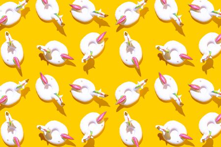 Inflatable unicorn pool toy pattern on bold yellow background. Minimal summer concept.の写真素材