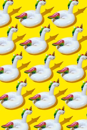Inflatable unicorn pool toy pattern on bold yellow background. Minimal summer concept.の写真素材