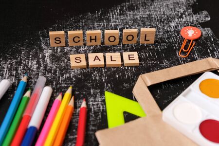 School sale with trendy shadow and different supplies on blackboard. Lettering school sale are made...