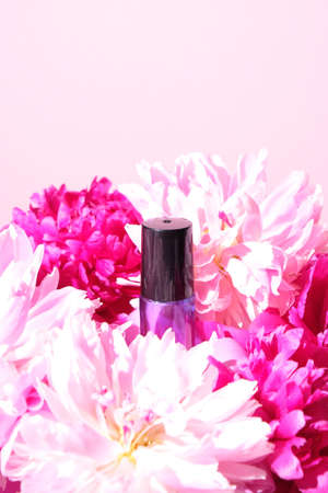 bottle of essential oil on a pink background with pink flowers