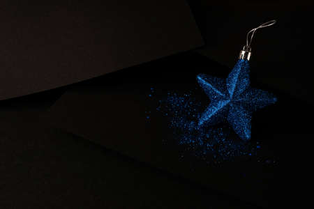 Blue shiny Christmas star on a matte black background. Minimalistic Christmas concert
