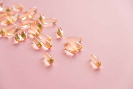 Pile of capsules Omega 3 on pink background. Close up, top view.