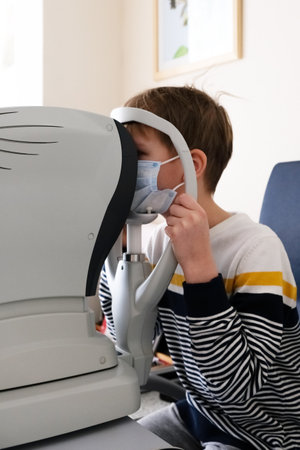 Checking the childs vision. Optometrist examines a patient s boy with special ophthalmic equipment in a modern clinic.の写真素材