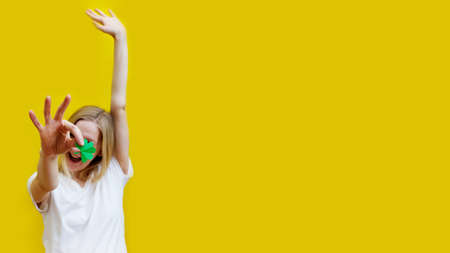 Shamrock in hand of young women in front of her face. Girls face on yellow background. Selective focus.の写真素材
