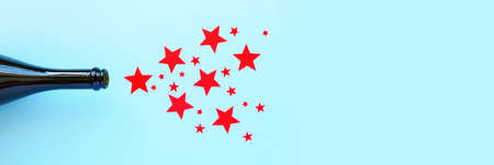 Star salute from a bottle of champagne. The concept of the anniversary with red stars on blue background. The red star is the symbol of the army. February 23 conceptの写真素材