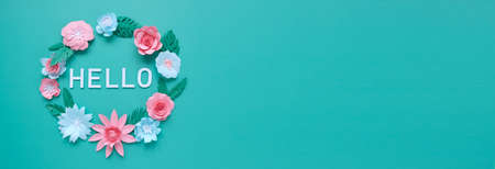 Hello, spring. Round frame witn pink and blue paper flowers and green leaves on neo-mint background.