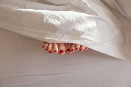 Soft photo of womans feet under a blanket, top view pointの写真素材