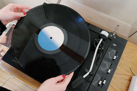 The girl puts the record in the player