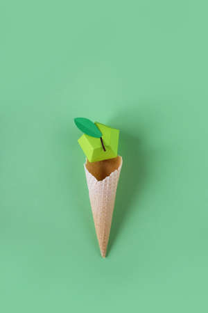 Waffle cone with paper fruits on green background. Fruits icecream conceptの写真素材