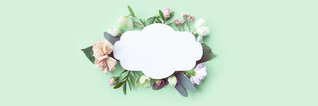 Vintage floral frame with rosebuds, delicate white flowers, branches, leaves and petals on a green background. Long format for webの写真素材