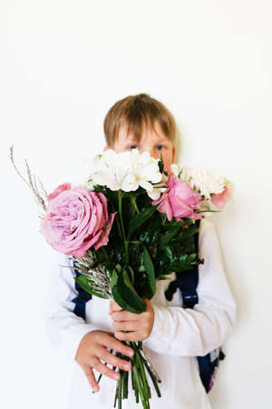 The first-grader with a bouquet on a white background. 7 years old