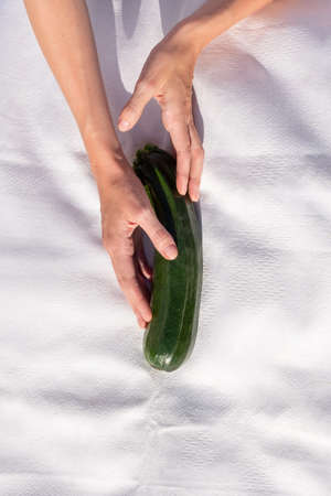 Fresh organic zucchini in female hand on white background. the concept of choiceの写真素材