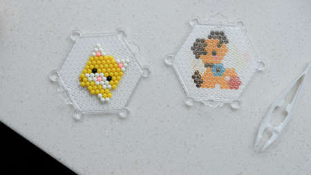 The child lays out an aqua mosaic in the form of a cats muzzle