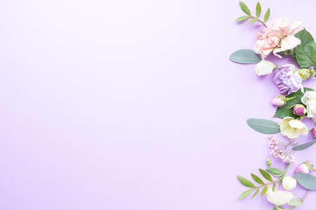Floral frame with pink roses, white flowers, branches, leaves and petals on purple background. Flat lay, top viewの写真素材