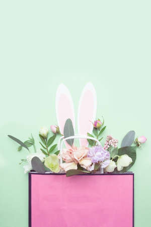 The Easter bunnys ears peek out of a bag of flowersの写真素材