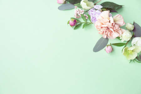 Floral frame with pink roses, white flowers, branches, leaves and petals on green background. Flat lay, top viewの写真素材