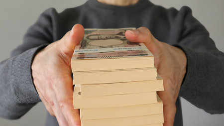 Close-up of a person holding a stack of billsの写真素材