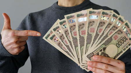 A person holding a large number of 10,000 yen bills and pointing