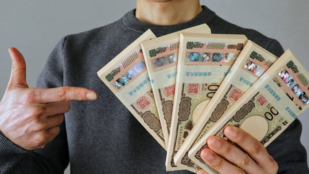 A person holding a wad of bills and pointing