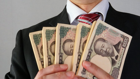 Japanese businessman holding a wad of billsの写真素材