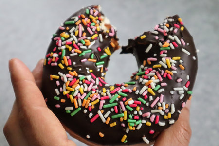 Person holding a half-eaten donutの写真素材