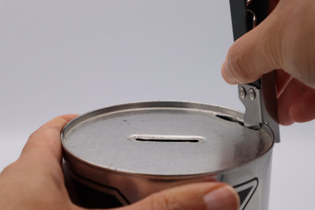 Person opening a piggy bank with a can openerの写真素材