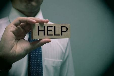A person holding a building block with the word HELP written on itの写真素材