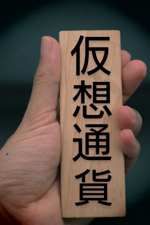 A person holding a wooden block with Japanese kanji characters written on itの写真素材