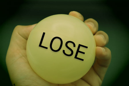 A person holding a ball with the word LOSE written on itの写真素材