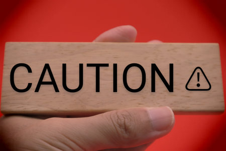 A person holding a building block with the word CAUTION written on it.の写真素材