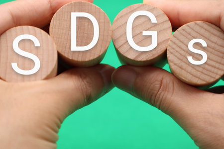 A person holding a building block with the words SDGs written on itの写真素材