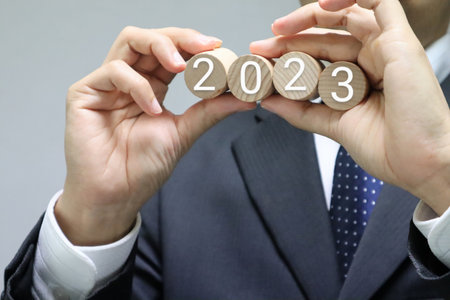A person holding a building block with the number 2023 written on it