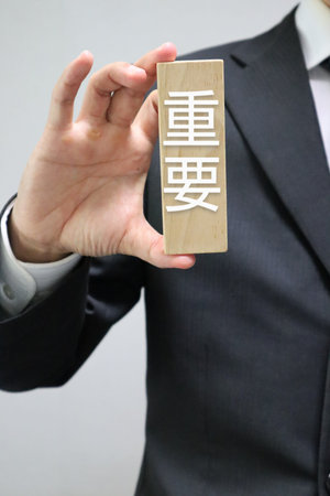 A person holding a building block that says "important"の写真素材
