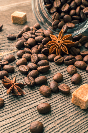 Coffee beans into glass jar table with csugar and anise on the woodenの写真素材