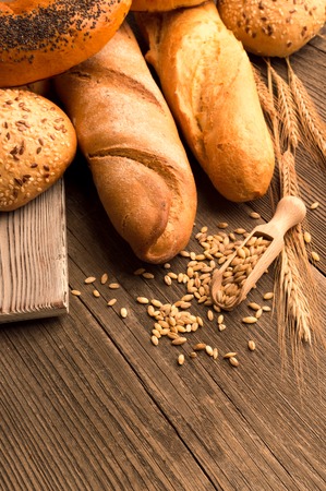 Spoon with grain, bread and buns on the wooden deskの写真素材