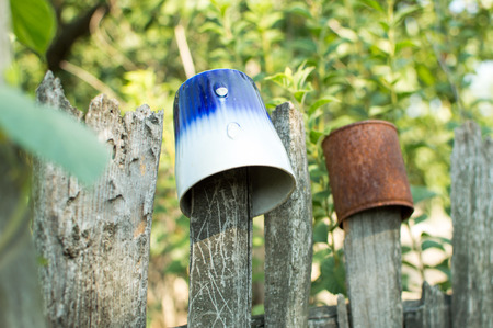 Broken old cup on the wooden fenceの写真素材