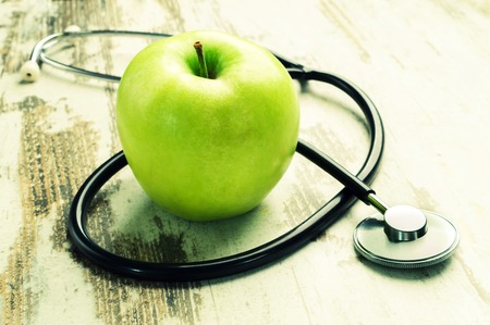 Good health. Green apple with medical stethoscope.の写真素材
