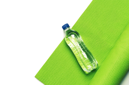Fitness concept - green yoga mat and bottle of water on the white backgroundの写真素材