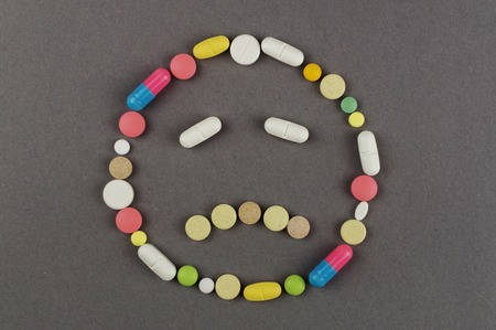 Unhappy smile created from colored pills. Medical concept.