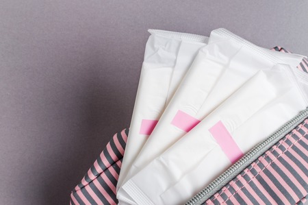 Menstrual tampons and pads in cosmetic bag. Menstruation cycle. Hygiene and protection.