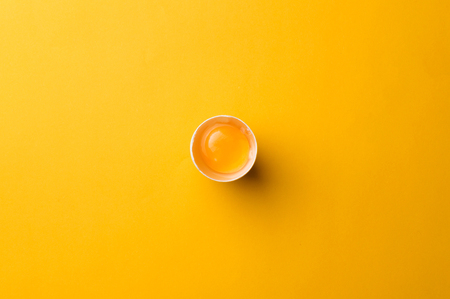 White egg and egg yolk on the yellow background.の写真素材