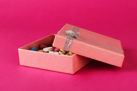 Gift box with pills on a pink backgroung. Medicine present concept.