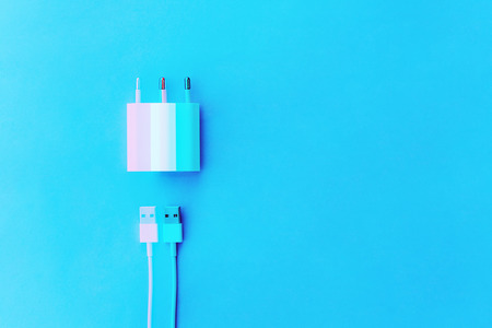 white ?able phone chargers on blue background. Top view. Objects on a simple background. Digital signal glitch effect (rgb shift, slices). Screen errorの写真素材