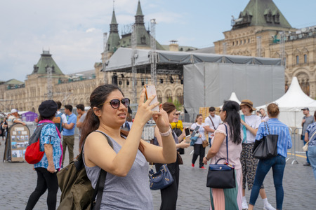 MOSCOW, RUSSIA - JUNE 04, 2019: A female tourist takes pictures on her smartphone sights on Red Square in Moscowのeditorial素材