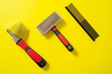 Close up grooming brush, special professional comb and furminator, for dogs and cats grooming. On bright yellow background. Concept of pets hair care and treatment, copy space.の写真素材