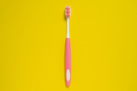 Pink and white tooth brush on bright yellow background. Isolated, studio, copy space for any text or design work.の写真素材