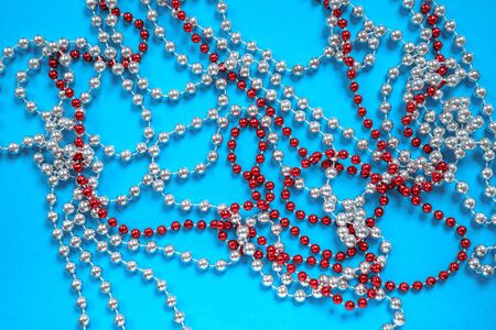 Red and white beads on bright blue background. Christmas or New year tree decoration, home holiday.