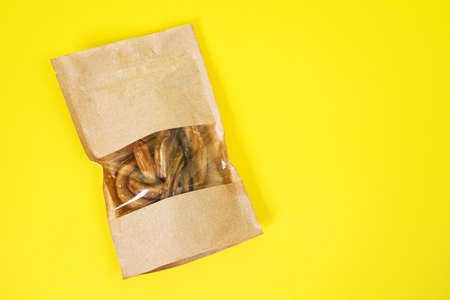 craft box with transparent top with tasty dried snacks for pets inside on yellow background, close up, top view, copy space for advertising text / Pet care. Pet supplies.の写真素材