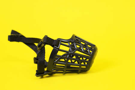 Top view of black plastic muzzle for a dog on a yellow background. Protecting the animal and others from attack. Do not pick up from the ground. Pet suppliesの写真素材