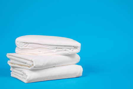 close up fresh white folded linens on a blue background. Room service maid cleaning hotel room.